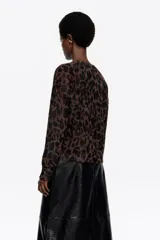 Cárdigan corto de manga larga con escote redondo y cierre frontal de botones, confeccionado en tejido de pelo con estampado de leopardo en tonos marrón y negro.