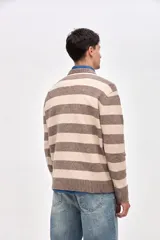 Buzo de punto con diseño de rayas horizontales en azul marino y beige, cuello redondo y puños acanalados. Presenta un pequeño bordado de estrella en la manga.