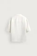 Camisa tipo kimono de corte relaxed fit, color celeste, confeccionada en tejido fluido de viscosa y lino. Presenta cuello con solapas de muesca, manga corta y cierre frontal cruzado con doble botonadura.