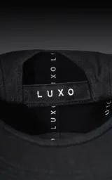 Gorra de gabardina negra con visera curva y ajuste trasero de velcro. Presenta un bordado frontal con el número "90" en color rojo con borde blanco.