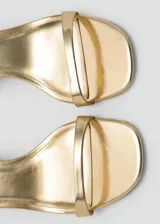 Sandalia de tacón cuadrado color dorado, con tira delgada en la parte delantera y pulsera ajustable con hebilla en el tobillo.