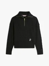 Sweater de punto negro con textura cableada, cuello alto con medio cierre de cremallera metálica dorada, mangas largas y detalle de logo bordado en el bajo.