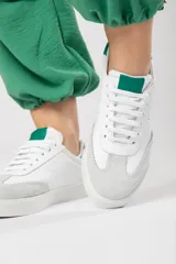 Zapatillas acordonadas de cuero color blanco con puntera de gamuza gris y detalles en verde.