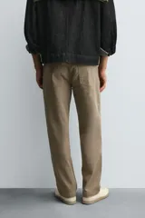 Pantalón de corte recto confeccionado en tejido de algodón con elasticidad. Presenta diseño de cinco bolsillos, cierre frontal con cremallera y botón.