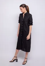 Vestido largo negro de lino y viscosa, abotonado al frente con alforzas en la parte central, mangas largas con elástico en los puños y cuello camisero.