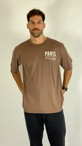 Remera de algodón color café, con cuello redondo, mangas cortas y corte holgado. Presenta un estampado tipográfico en el pecho con la palabra Paris.
