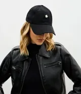 Gorra de sarga de algodón color negro, con ala curva y parche metálico en forma de estrella en la parte frontal. Cuenta con ajuste de hebilla en la parte posterior.