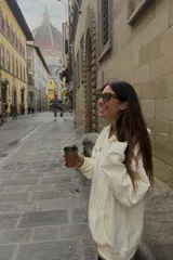 Buzo con capucha color crudo, de corte holgado y manga larga, con bolsillo canguro frontal.