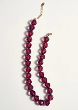 Collar corto de diseño multicapa, compuesto por cuentas facetadas de acrílico en tonos rojo, ámbar y verde.