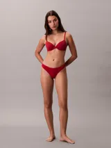 Bombacha tipo colaless Calvin Klein de la línea Ideal Cotton, confeccionada en mezcla de algodón elástico. Presenta un diseño minimalista con cintura fina y flexible, y cuenta con el logo de la marca estampado en el lateral.
