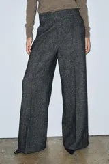 Pantalón de corte recto confeccionado en tejido con mezcla de lana. Presenta tiro medio, cintura con trabillas, bolsillos laterales y traseros, y detalle de nervio frontal. Cierre mediante cremallera, botón y ganchos metálicos.