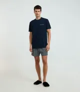 Conjunto de pijama corto masculino confeccionado con algodón y viscosa. Incluye remera azul marino de manga corta con bolsillo en el pecho y short a rayas verticales blancas y azules con cintura elástica.
