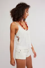 Camisola negra de satén con tirantes finos ajustables, escote en V y detalles de encaje floral en el contorno del pecho y los laterales. Presenta pequeñas aberturas laterales.