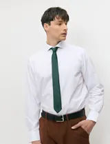 Camisa de vestir blanca de manga larga, con cuello clásico y cierre frontal de botones.