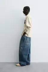 Camiseta de manga larga con cuello redondo, corte relaxed fit y tejido con estructura waffle. Presenta estampados y bordados combinados a contraste en el delantero.