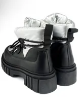 Borcego de caña media color negro con detalles plateados, cordones negros y suela track.