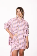 Camisa oversize a rayas celestes y blancas, con cuello camisero, manga larga y hilera de botones dorados metálicos.
