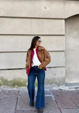 Campera tipo bomber color camel, confeccionada en gamuza, con bordados decorativos en tonos natural y bordó en las mangas y hombros. Presenta cierre frontal y diseño holgado.