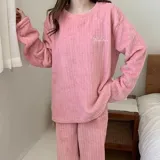 Conjunto de pijama de dos piezas confeccionado en tela de plush texturizada con diseño de rayas verticales en relieve. Incluye una remera de manga larga con cuello redondo y un pantalón de corte holgado. La remera presenta un pequeño bordado decorativo en el pecho.