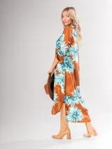 Vestido camisero largo con estampado floral en tonos rojos y negros, con cuello camisero, abotonadura frontal y mangas largas con puños abotonados.