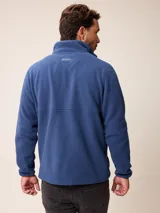 Campera de polar tipo sherpa en color azul, con cierre frontal completo, cuello alto y bolsillos laterales. Presenta un pequeño logo bordado en el pecho.