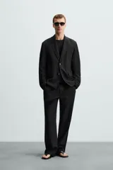 Blazer negra relaxed fit confeccionada en tejido fluido con mezcla de lyocell. Cuello con solapas de muesca y manga larga. Bolsillos de solapa en cadera. Detalle de bolsillo interior. Cierre frontal de botonadura.