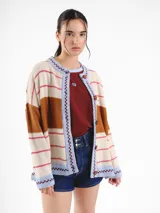 Cardigan tejido de punto jacquard en tonos bordó y rojo con rayas, de corte oversize, cuello redondo y cierre frontal con botones carey. Presenta detalles bordados en contraste y monograma en la espalda.