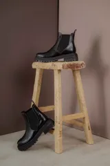 Botas tipo Chelsea de cuero con acabado vintage, diseño de caña media con paneles elásticos laterales y suela track robusta.