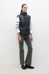 Chaleco negro de cuero sintético con cuello alto, cierre frontal con cremallera y bolsillos laterales con solapa.