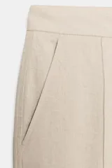 Pantalón de tiro medio confeccionado en lino color beige, de pernera recta con nervios marcados en el delantero. Posee bolsillos frontales, falsos bolsillos de vivo en la espalda y cierre frontal con cremallera, botón interior y gancho.