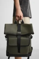 Mochila verde militar con acabado engomado, solapa superior con cierre de hebilla y cremallera, bolsillo frontal con cierre imantado, compartimento interno para laptop de hasta 13 pulgadas, asa de mano superior, correas de hombro ajustables y espalda acolchada. Base de cuero sintético negro.