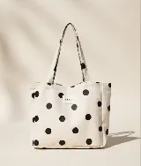 Bolso tipo tote bag de algodón color beige con estampado de lunares negros y etiqueta central con logo de la marca.