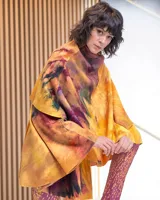 Capa asimétrica multicolor de lana merino afieltrada, teñida artesanalmente con acuarelas en tonos amarillos, naranjas, azules y violetas.