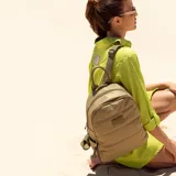 Mochila capitoneada color verde militar, confeccionada en nylon. Tiene apertura superior con cierre y tiradores metálicos, bolsillos internos, bolsillo frontal con cierre metálico, correa corta de mano y correas de galón regulables para colgar en la espalda.