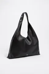 Bolso de hombro de tamaño maxi confeccionado en piel vacuna, con estructura blanda, asa de piel y logo metálico frontal.