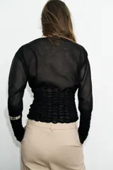 Jersey de punto semitransparente color crudo, con cuello redondo, manga larga y detalles elásticos de nido de abeja en el torso y en los puños.