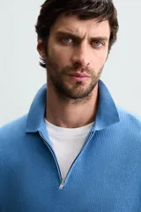 Polo de manga corta, color azul medio, tejido en punto perlado con cuello solapa y cierre frontal de cremallera.