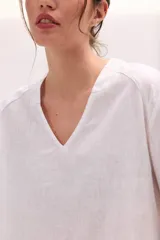 Blusa de lino color lila, de corte relajado y mangas largas amplias, con escote en V y ruedo curvo.