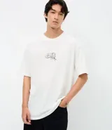 Remera de corte relajado color blanco, con cuello redondo y manga corta. Presenta un estampado pequeño en el centro del pecho con la inscripción 'Most Wanted' y el diseño de los Hermanos Metralla.