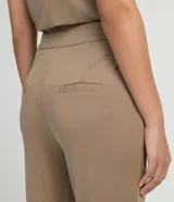 Pantalón recto color beige en tejido modal, con cintura alta, cierre con botones y cremallera, dos bolsillos laterales y corte frontal.