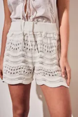 Short tejido de punto con diseño de ondas y calados, color blanco. Presenta cintura elástica acanalada y corte mini.