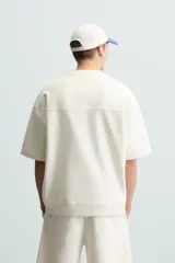 Sudadera de manga corta color marrón oscuro, con cuello redondo y bajo acabado en rib. Presenta un corte relajado y holgado (boxy fit).