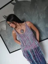 Top tejido artesanal de silueta suelta, con breteles anchos y escote halter. Diseño calado con flecos largos multicolores que aportan movimiento y textura.