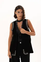 Chaleco negro de cuero descarne con silueta relajada y detalles de ojalillos metálicos plateados distribuidos en los bordes y sisas.