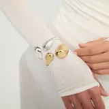 Pulsera rígida dorada bañada en oro de 18k, con diseño abierto y extremos en forma de gota de diferentes tamaños.