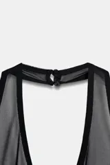 Body de cuello halter con paneles de malla transparente en el escote. Presenta un diseño ajustado con espalda descubierta, cierre de botones en el cuello y cierre en el bajo.