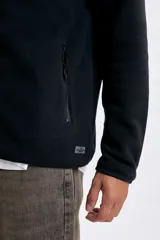 Campera de polar color negro con cierre frontal completo y cuello alto. Diseño básico de corte recto con bolsillos laterales.