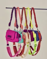 Cartera tipo bandolera acolchada color turquesa, con correa trenzada color salmón y logo bordado en el frente.