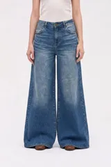 Jean de tiro medio con corte wide leg, confeccionado en denim azul con efecto lavado. Presenta cierre frontal con botón y bolsillos laterales y traseros.