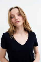Remera negra de manga corta, con escote en V adornado con detalle de broderie.